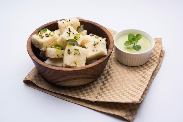 Khaman white Dhokla feito de arroz ou urad dal é um café da manhã popular ou receita de lanches de Gujarat, Índia, servido com chutney verde e chá quente. Foco seletivo