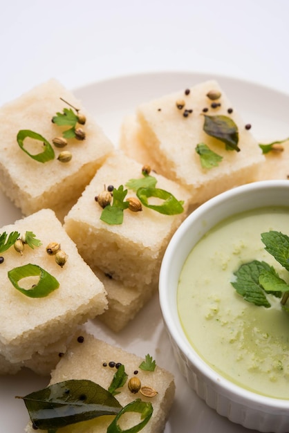 Khaman white Dhokla feito de arroz ou urad dal é um café da manhã popular ou receita de lanches de Gujarat, Índia, servido com chutney verde e chá quente. Foco seletivo