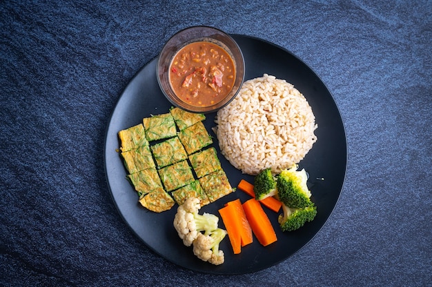 Khao khluk kapi (arroz tradicional de camarão tailandês) em prato sobre comida local escura da tailândia