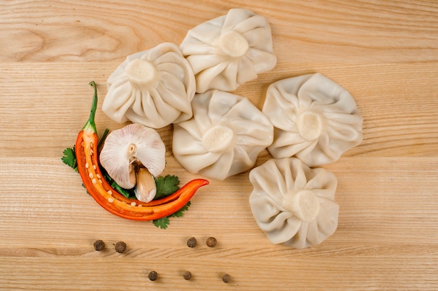 Khinkali tradicional - bolinhos da Geórgia, prato nacional da culinária georgiana, com pimenta vermelha, alho branco e salsa verde estão deitados em cima da mesa