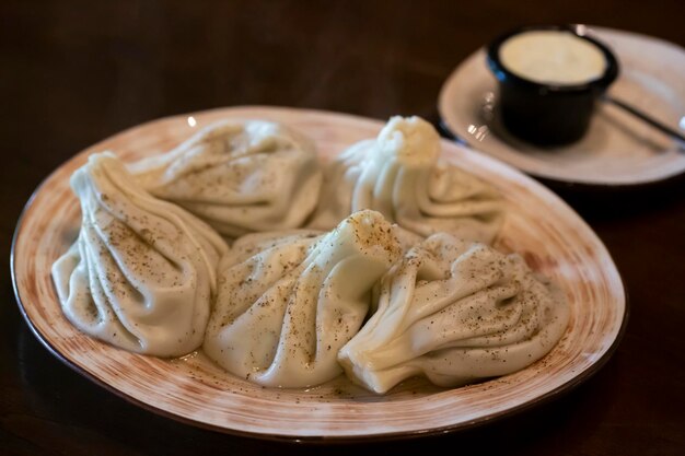 Khinkali traditionelle georgische Knödel in einem weißen Teller mit weißer Sauerrahmsoße