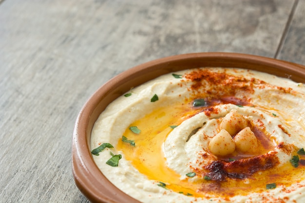 Kichererbsenhummus in der Schüssel auf Holztisch, Kopienraum