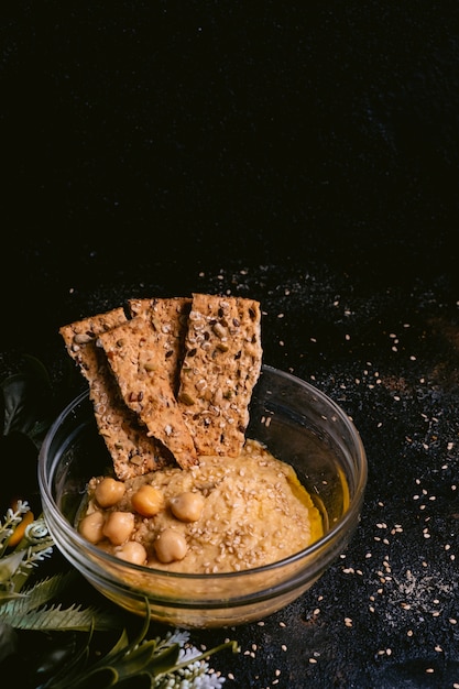 Kichererbsenhummus mit indischem Sesam in der Glasschüssel auf Holztisch. Veganes Essen