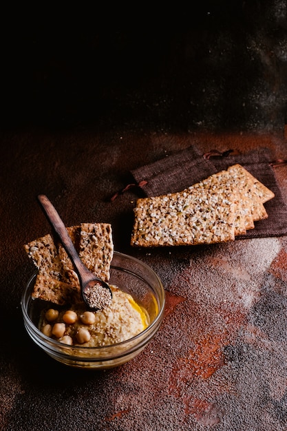 Kichererbsenhummus mit indischem Sesam in der Glasschüssel auf Holztisch. Veganes Essen