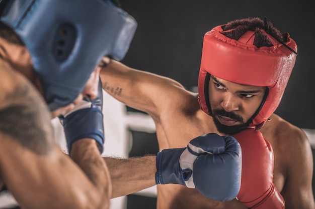 Kickboxen Kickboxer in schützenden Hemlets kämpfen und sehen entschlossen aus