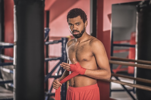 Kickboxer. Afroamerikanischer Kickboxer, der vor dem Training einen Verband an seiner Hand tippt