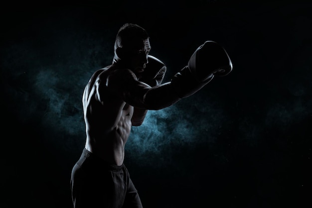 Foto kickboxer em luvas pretas posando em um fundo de fumaça o c