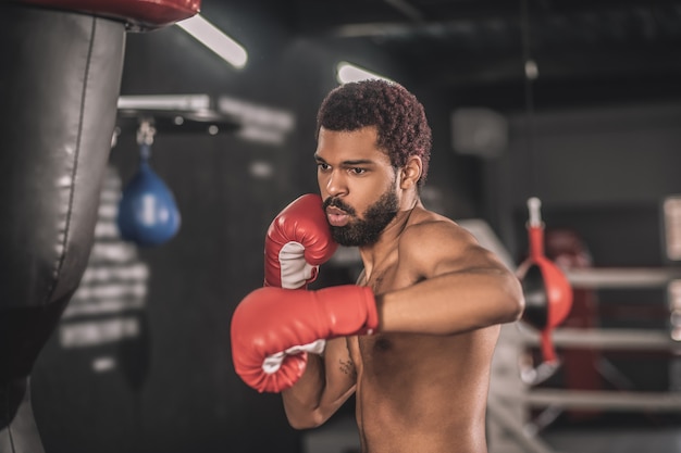 Kickboxer. Kickboxer jovem de pele escura se exercitando em uma academia