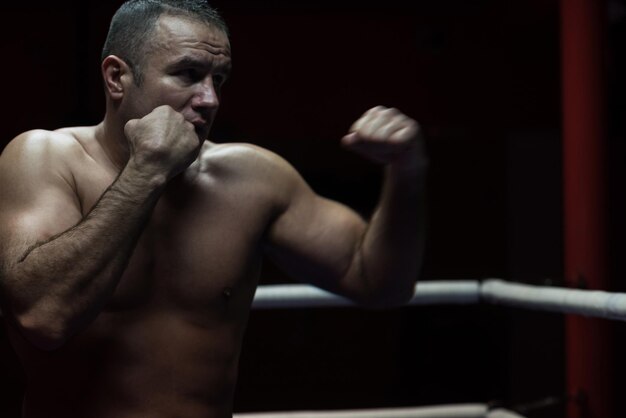 kickboxer profesional con las manos en posición de artes marciales entrenando para la pelea en el ring de entrenamiento