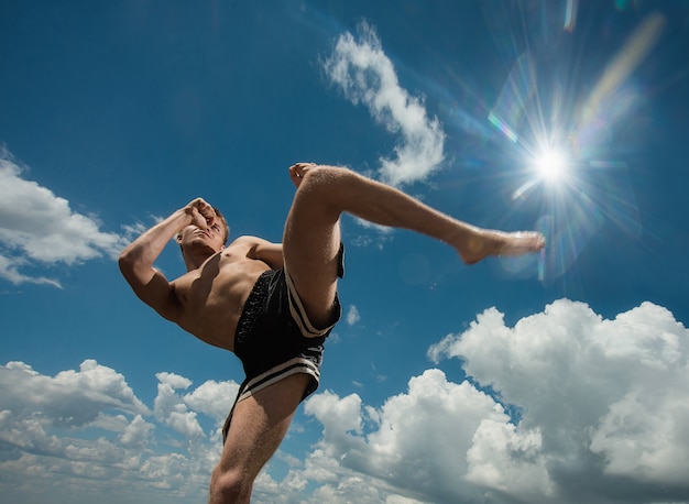 Kickboxer tritt im Sommer im Freien gegen das Meer.