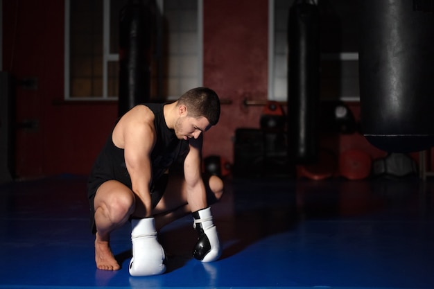 Kickboxkämpfer in Boxhandschuhen auf Knien stehend.