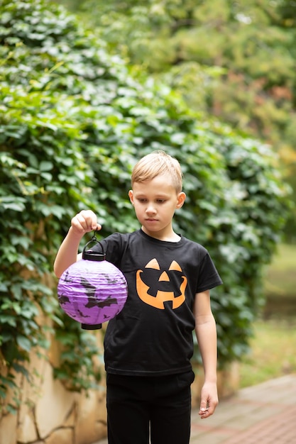 Kid boy adolescente sosteniendo linterna de papel. Truco o trato para niños en las vacaciones de Halloween. Actividad al aire libre para niños.