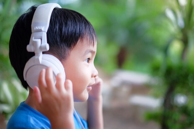 Kid escucha música con auriculares en casa. Cara lateral mirando con espacio de copia.