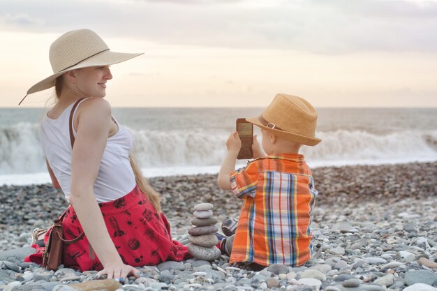 Kid fotografía a su madre por teléfono, costa del mar