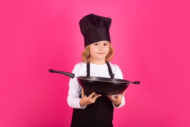 Kid Küchenchef kochen Kochen mit Pfanne Kinder kochen Chef Kid Junge macht gesunde Ernährung Porträt des kleinen Kindes in Kochmütze auf Studio-Hintergrund isoliert Kid Küchenchef Garprozess