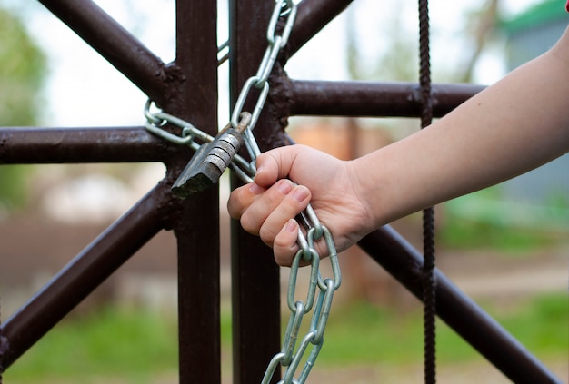 Kid mano sostiene cerradura de cadena de hierro metálico cerrado T