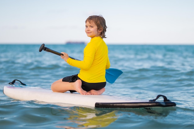 Kid paddle boarder criança menino remando em paddleboard estilo de vida de verão saudável esporte aquático de verão sup