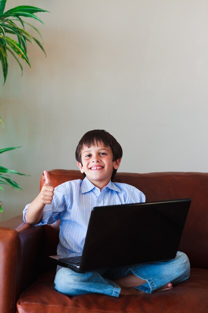 Kid usando seu laptop com o polegar para cima