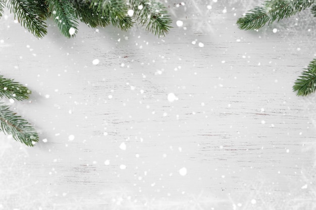 Kiefernblätter verziert als Rahmen auf einem weißen hölzernen Hintergrund mit Schneeflocken. Frohe Weihnachten und Winterurlaub Hintergrund.