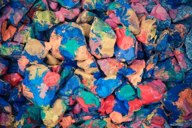 Kieselsteine gemalt helle farbige Farbe. Steinige Oberfläche mit verschiedenen Farben bedeckt. Abstrakte flache Linie Hintergrund.