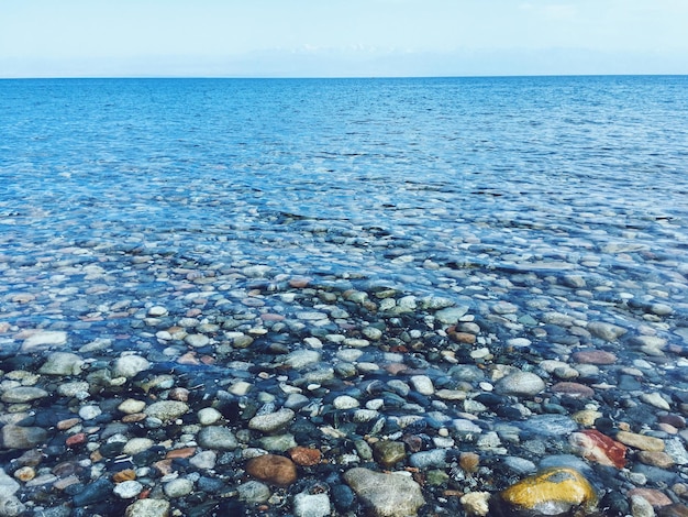 Kieselsteine im Meer gegen den Himmel