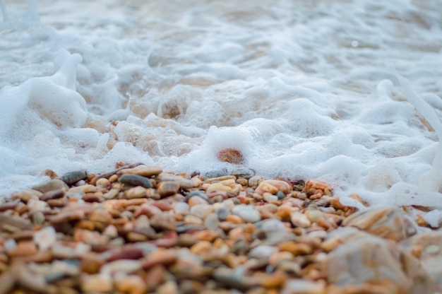 Kieselsteinfelsen und Meereswelle am Strand