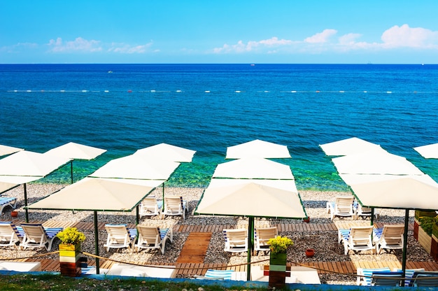 Kieselstrand mit Sonnenschirmen in Kemer, Türkei. Schöner Sommermeerblick. Reisezielkonzept