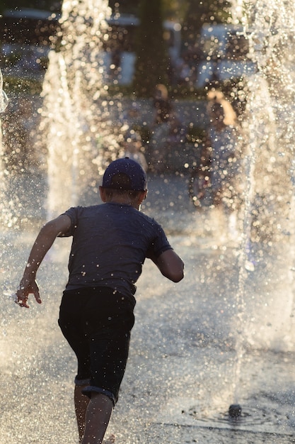 KIEV, UCRÂNIA - 05 de junho de 2018: Crianças alegres e felizes brincando em uma fonte de água e apreciando os fluxos de água em um dia quente. Verão quente.