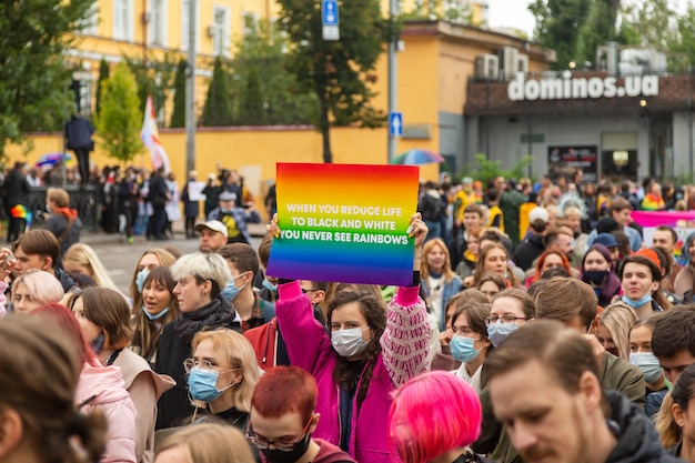Kiev, Ucrania - 09.19.2021: comunidad LGBTQ en el Desfile del Orgullo. Los participantes de la marcha con símbolos de arco iris están pasando por las calles de la ciudad. Una niña sostiene un cartel casero en una multitud.