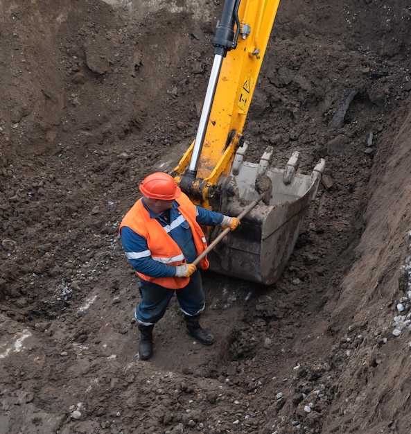 Kiev, Ucrania - 20 de mayo de 2021: Movimiento de tierras en el sitio de construcción de la ciudad. Trabajos de reparación en el sistema de alcantarillado de la ciudad. Trabajador en un traje especial con una pala.