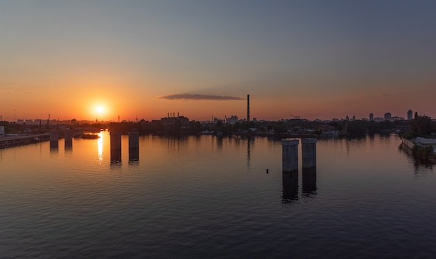 KIEV, Ucrania - 30 de mayo de 2018: Distrito industrial de Kiev en el distrito de Podil. Dnieper y el puerto fluvial. Vista desde el puente Rybalsky atirantado por la noche durante la puesta de sol