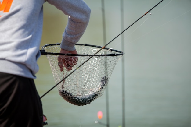 Kiew, Ukraine 16. April 2018. Ein Fischer schneidet eine Angelschnur für einen Fisch in einem Kescher ab.