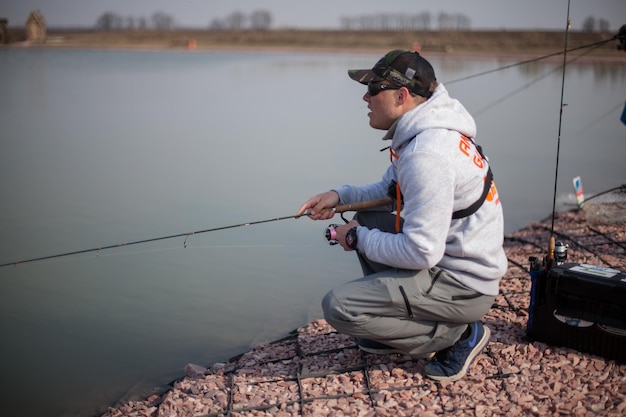 Kiew, Ukraine 16. April 2018. Kaukasischer Fischer fängt Fische mit einer Spinnrute auf dem See.