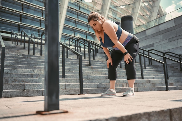 Killing Workout müde junge Plus-Size-Frau in Sportkleidung, die sich nach dem Training müde fühlt, während