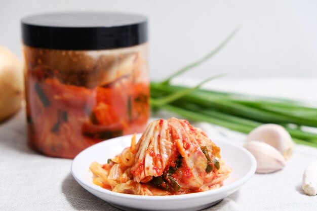 El kimchi se coloca en un plato blanco con los ingredientes sobre la mesa.