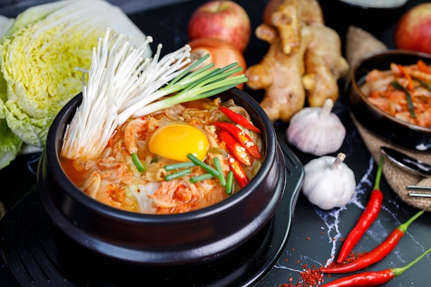 Kimchi Kohlsuppe in einer Schüssel mit Materialien des Kimchi auf schwarzem Hintergrund