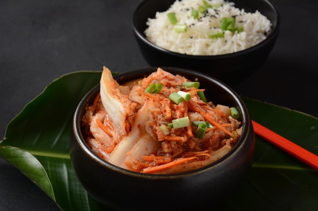 Kimchi und Reis in schwarzer Schüssel mit Essstäbchen Koreanisches Essen