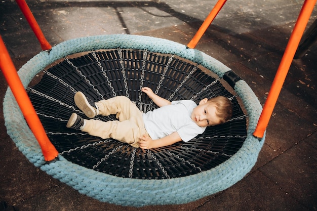 Kind 2-3 Jahre alt schaukelt auf einer runden Schaukel auf dem Spielplatz