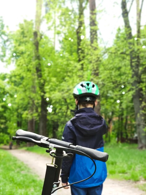 Kind allein im Park auf einem Roller mit Helm