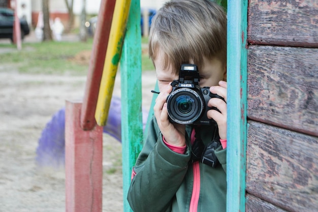 Foto kind auf der straße in einer jacke mit einer filmkamera hochwertiges foto