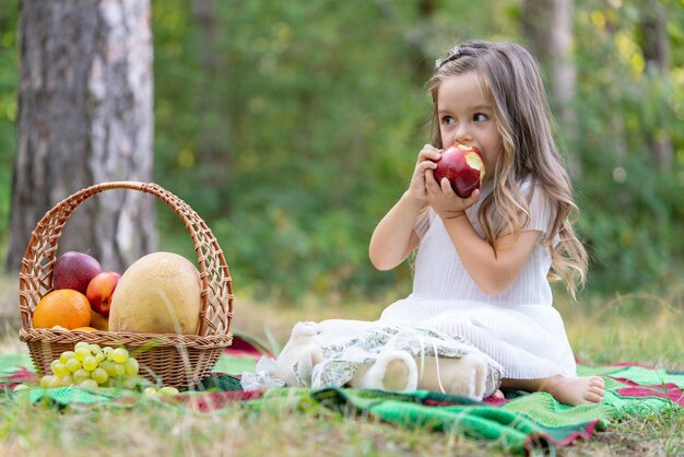 Kind auf Herbstpicknick, das Apfel isst Kleines Mädchen im Herbstpark