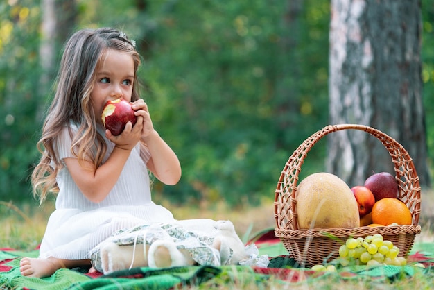 Kind auf Herbstpicknick, das Apfel isst Kleines Mädchen im Herbstpark