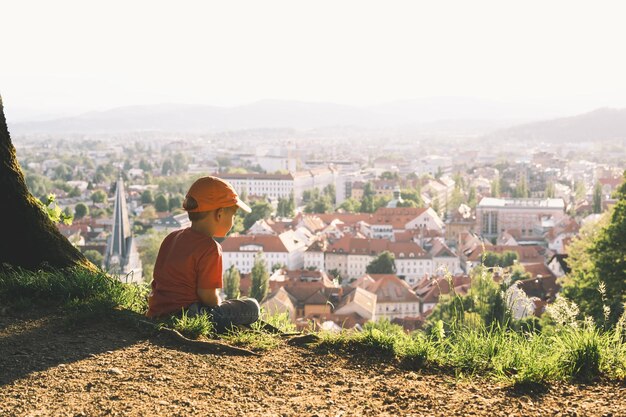 Kind auf Hintergrund von Ljubljana Slowenien Europa Familie im Freien im Frühling oder Sommer Kleiner Junge betrachtet Panorama der europäischen Stadt vom Hügel