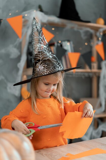 Kind bastelt Kürbisse für den Halloween-Feiertag. Lustige 