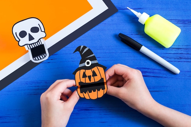 Kind bastelt toy Papierspielzeug Totenkopf und Jackolantern für Halloween