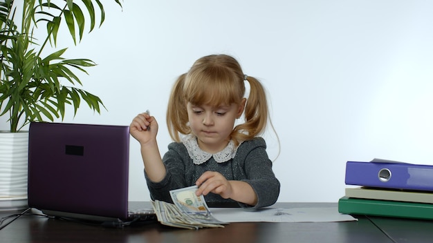 Kind Boss Mädchen zählt Dollar-Geld-Scheine Baby Geschäftsfrau Kind mit Geld sitzt im Büro