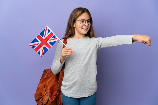 Kind, das eine Flagge des Vereinigten Königreichs über isoliertem Hintergrund hält und eine Geste mit dem Daumen nach oben gibt