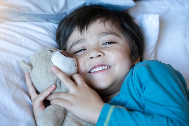 Kind, das in bett mit teddybären legt