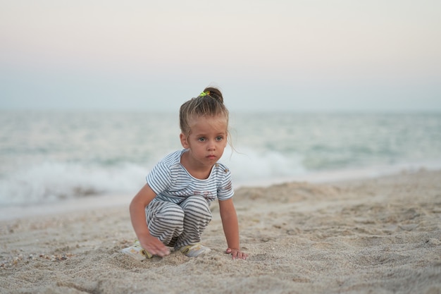 Kind, das mit Sand am Strand spielt