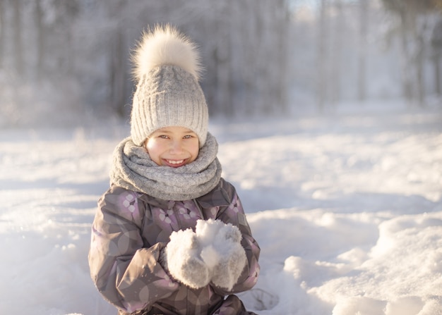 Kind, das mit Schnee im Winter spielt. Kinder fangen Schneeflocken